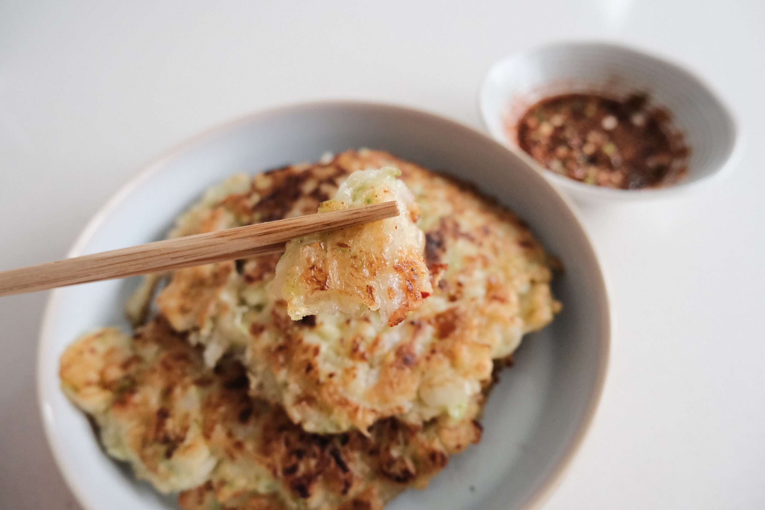 Close up picture of a piece of pancake with chopsticks