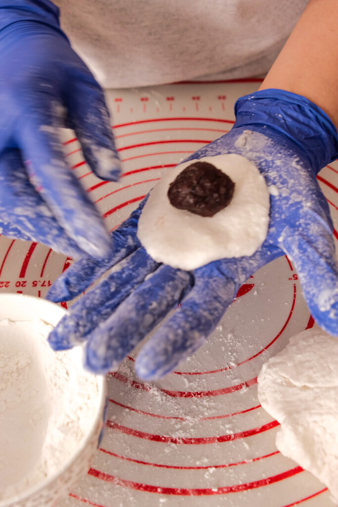 Placing red bean paste in sago dough