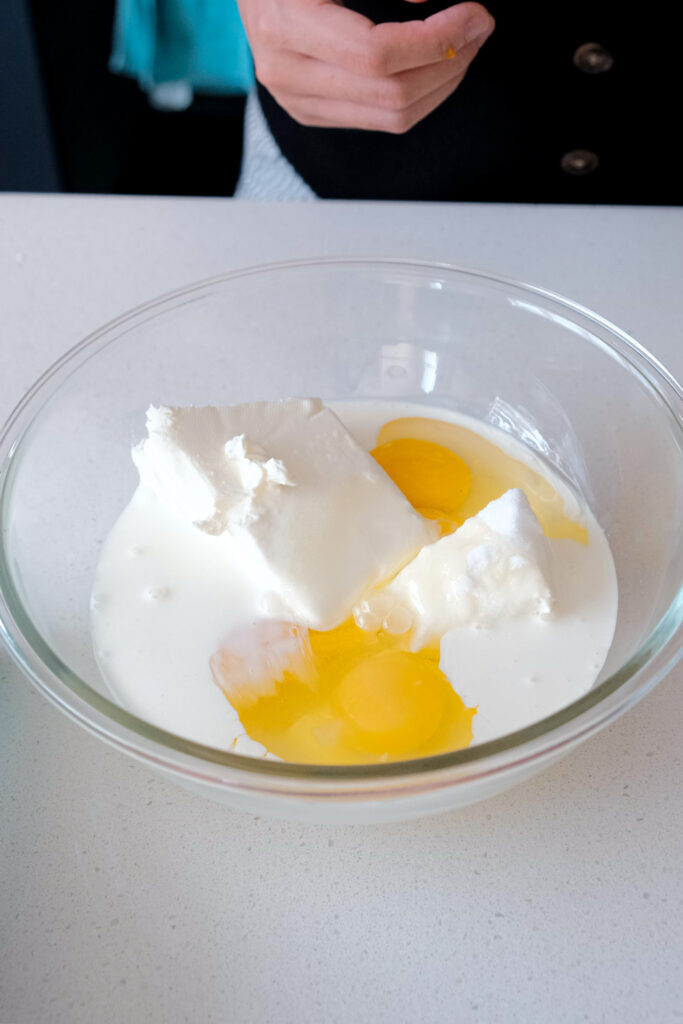 Cream cheese, sugar, whipping cream and eggs in bowl