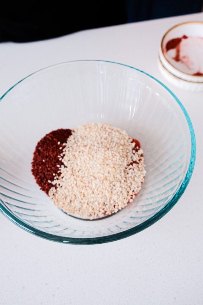 Adding chili flakes and sesame seeds into bowl