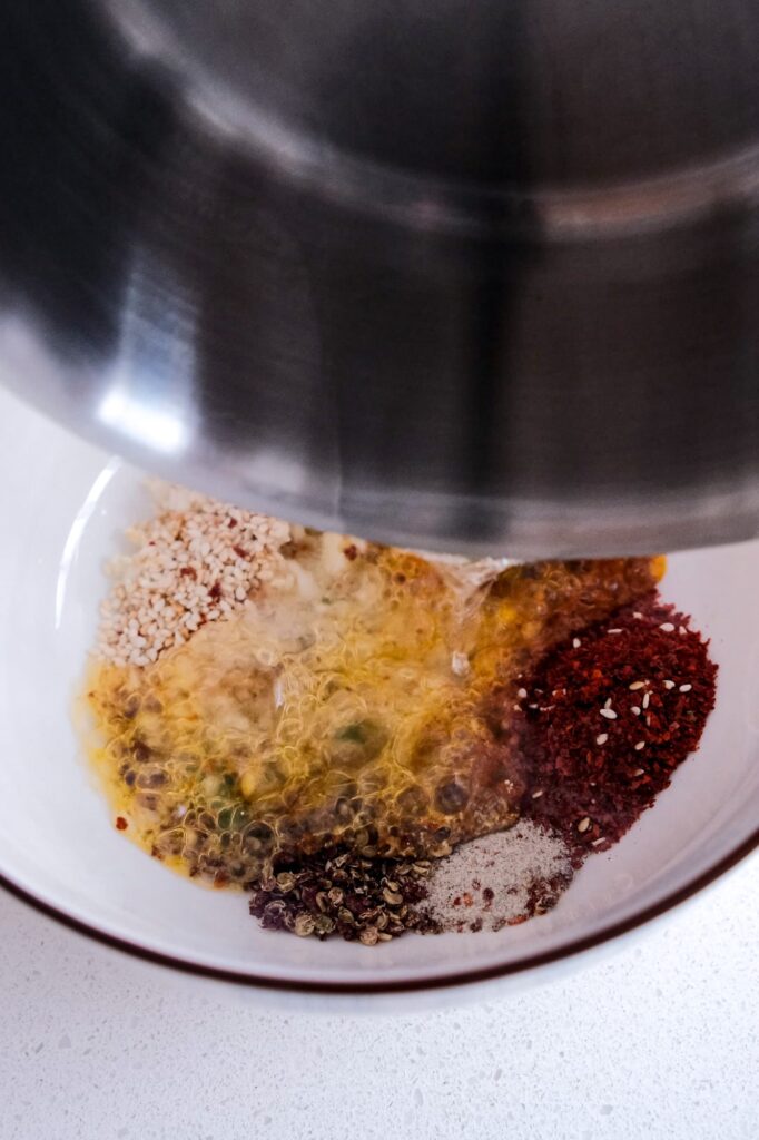 Pouring hot oil into the bowl of aromatics
