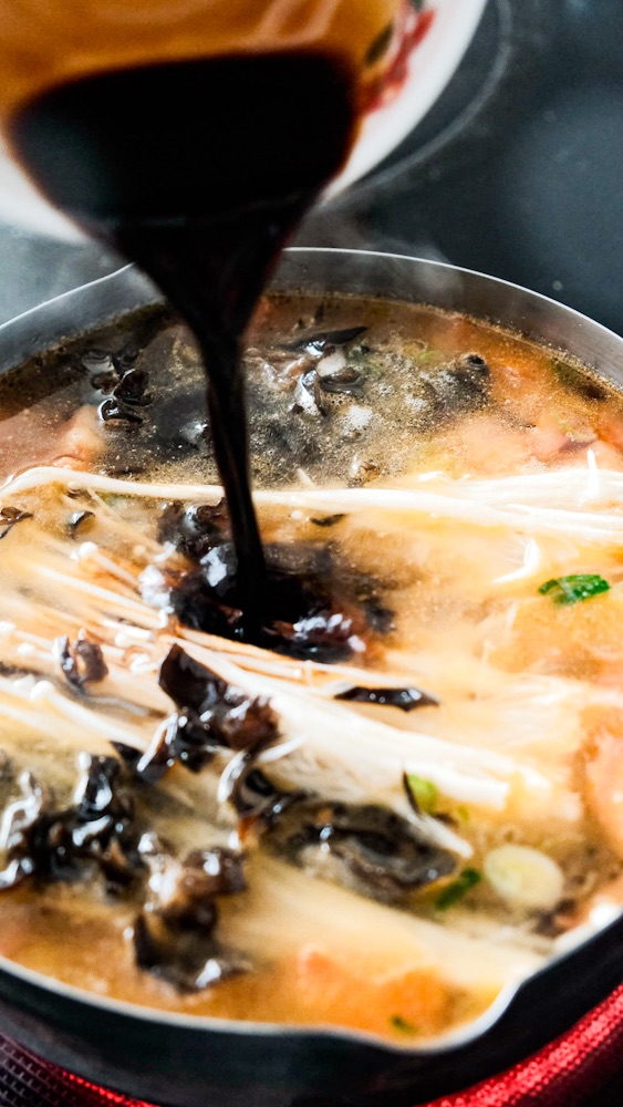 Adding soy sauce to the soup