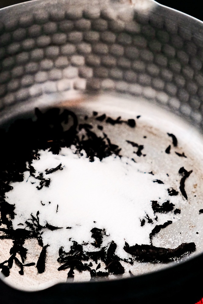 Adding tea and sugar in a pot